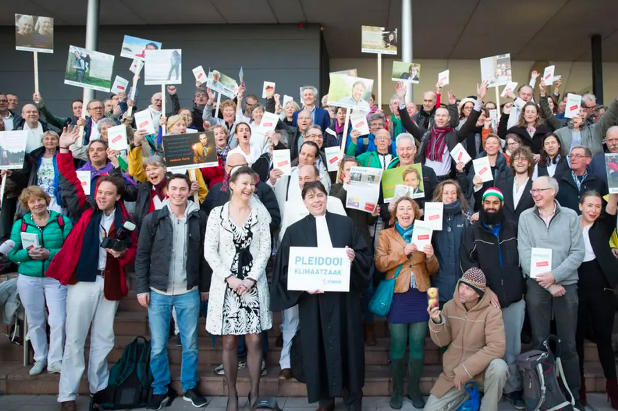 Nach sechs Jahren Gerichtsverfahren freut sich Urgenda über die erfolgreiche Klimaklage. Im Bild jubeln mehr als 50 Menschen mit Schildern in niederländischer Sprache in die Kamera. Foto: © Urgenda / Chantal Bekker